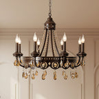 Front view of a lit Clérachic chandelier with a bronze-finish frame and amber crystal drops, in a room with pale panelled walls.