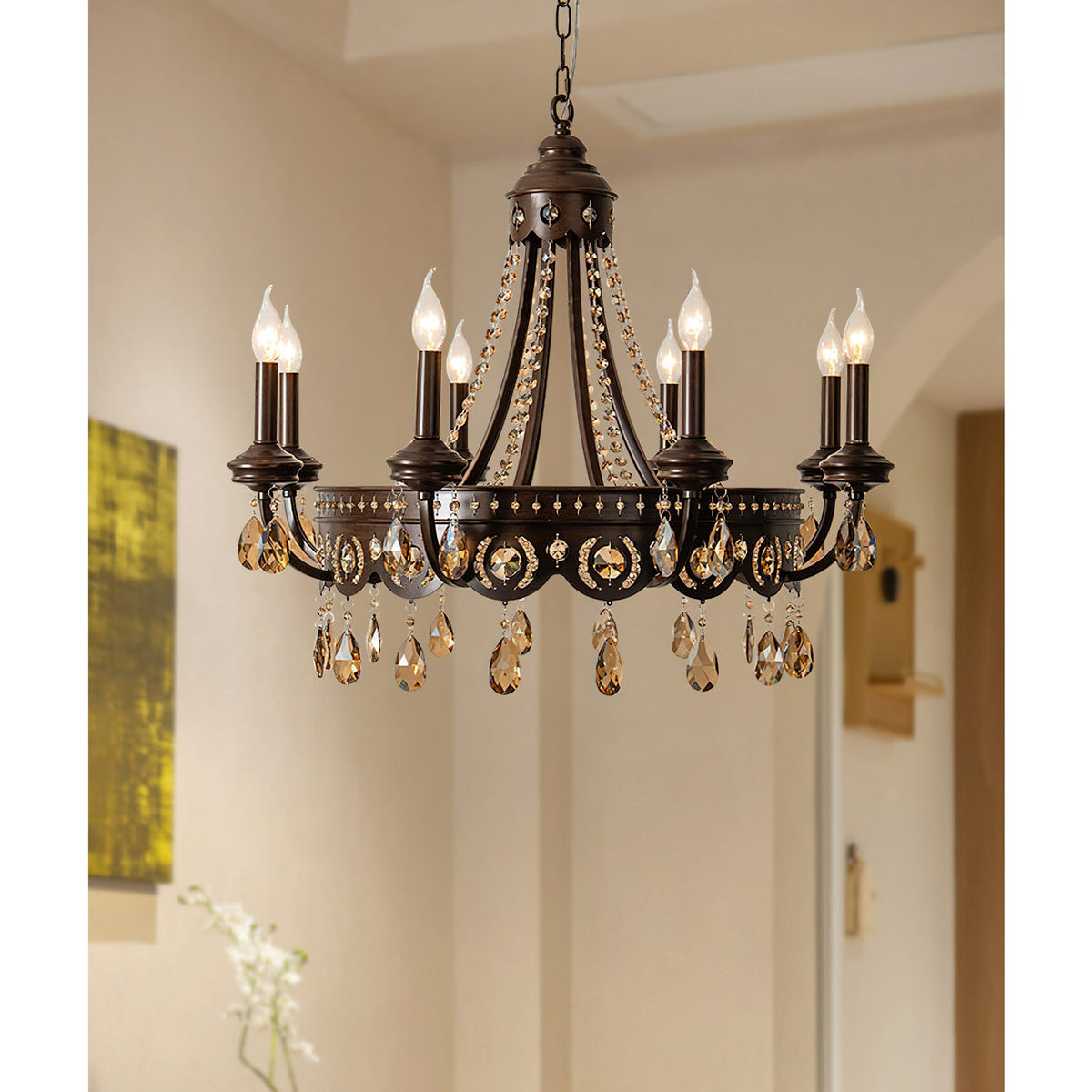 Clérachic chandelier with amber crystal drops lit in a pale hallway, with an arched doorway and a painting at the edge.