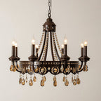 Bronze-finish Clérachic chandelier with amber crystals and six candle lights, lit against a plain beige wall.