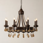 Lit Clérachic chandelier with a dark bronze-finish frame, beaded crystal garlands and amber teardrop crystals, on a cream wall.