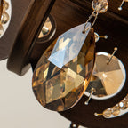 Close view of a faceted amber crystal drop hanging from the bronze-finish ring of this Clérachic chandelier.