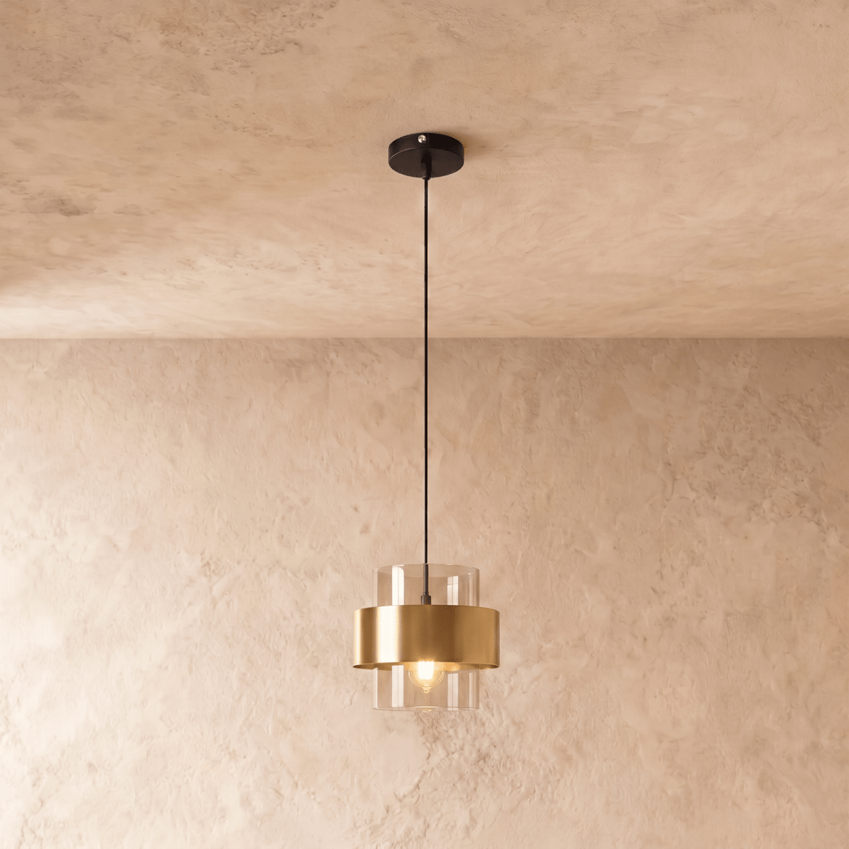 Clérachic glass cylinder pendant light with a brass midi band, hanging on a black cord from a round ceiling plate against a plastered wall.