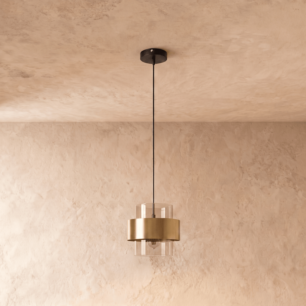 Straight-on view of the Clérachic cylinder pendant light, its clear glass shade and brass band suspended below a plain ceiling.