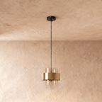 Straight-on view of the Clérachic cylinder pendant light, its clear glass shade and brass band suspended below a plain ceiling.