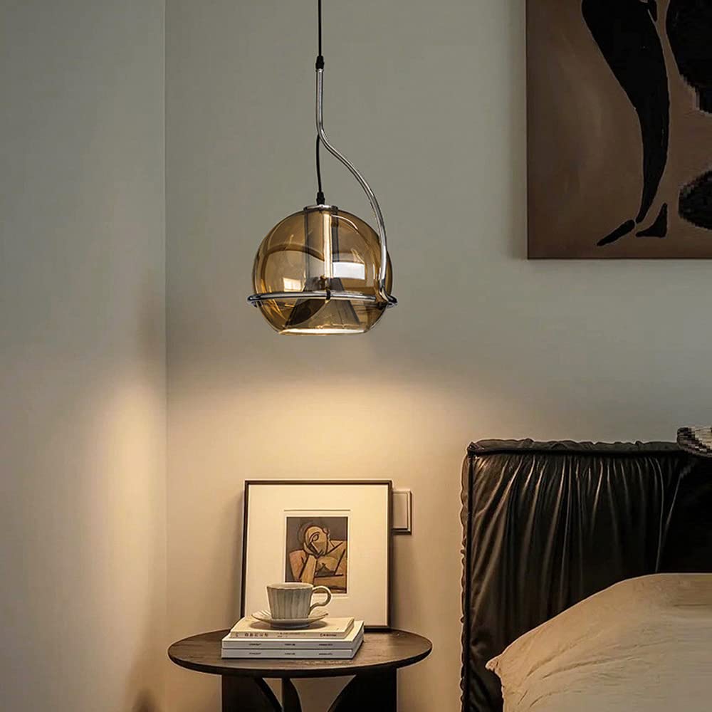 Clérachic Amber Glass Dome Pendant Light glows over a dark wood bedside table stacked with books and a cup.