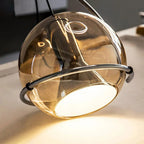 Close-up of the Clérachic Amber Glass Dome Pendant Light, warm light spilling from the white diffuser at its base.