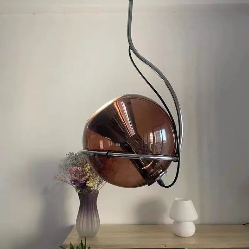 The Clérachic Amber Glass Dome Pendant Light hangs above a wooden table with a vase of dried flowers.