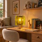 Green and gold Clérachic table lamp on a wooden desk, with a toy giraffe, a teddy bear and a row of children's books.