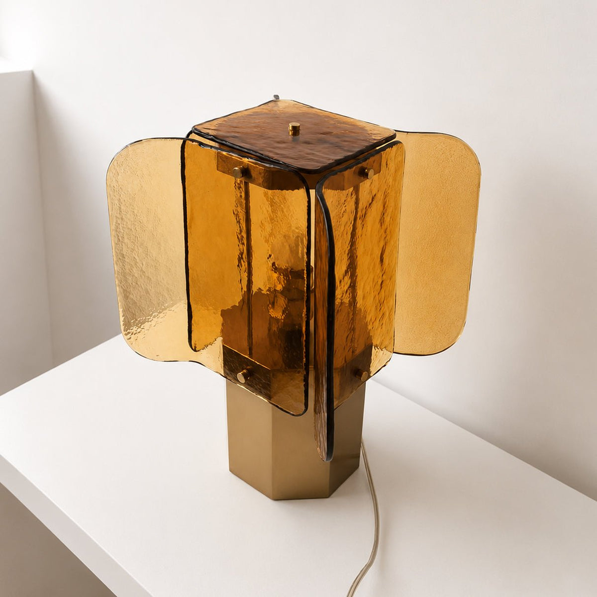 Rear-angled view of this Clérachic table lamp, showing the dark top plate and fanned amber glass panels over the brass base.