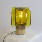 Green glass Clérachic table lamp lit on a draped white surface, with a black cord trailing from the brass base.