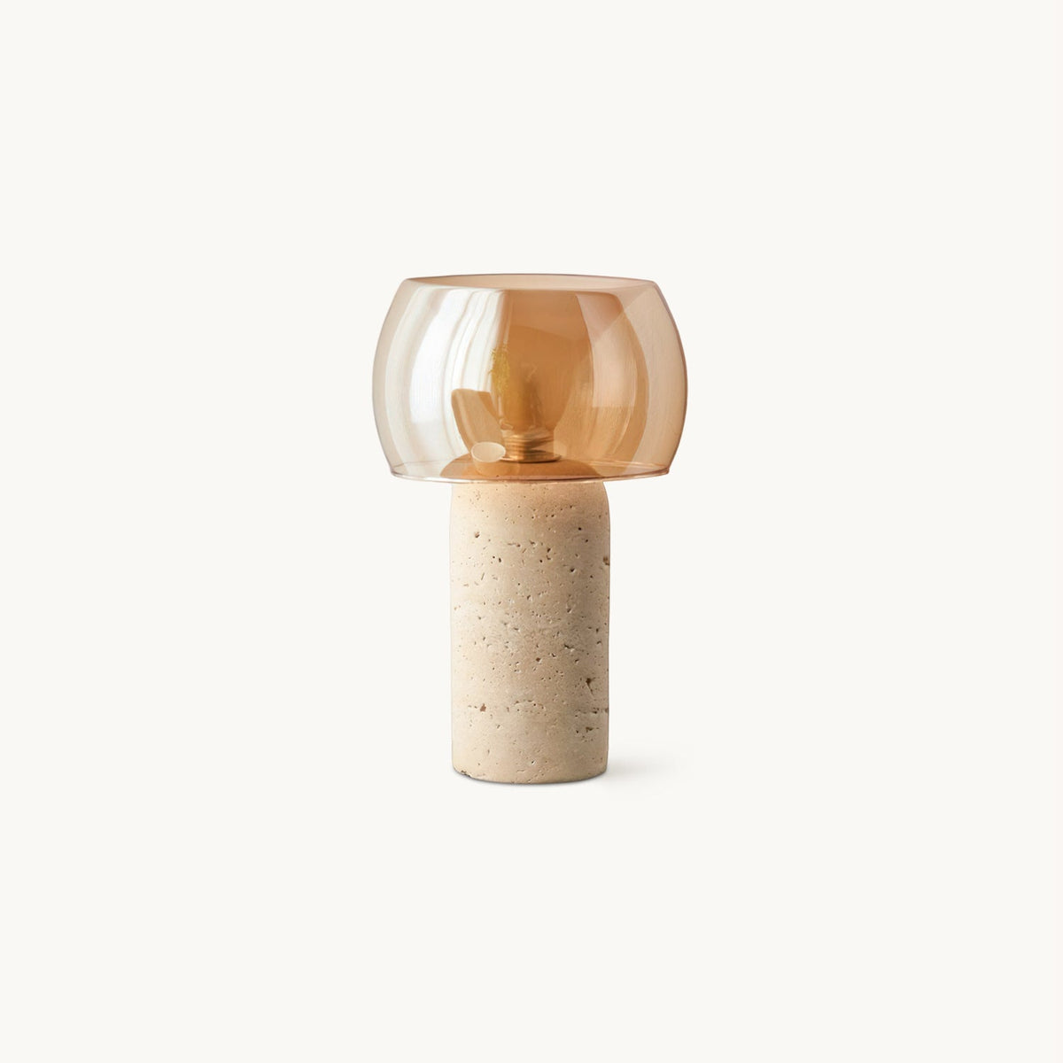 A Clérachic table lamp with an amber glass shade on a travertine column base, shown on a plain white backdrop.