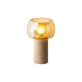 Cut-out of this Clérachic table lamp in its taller column form, lit, with an amber glass shade on a white backdrop.