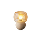 Cut-out of this Clérachic table lamp in its shorter sphere-base form, lit, with an amber glass shade on a white backdrop.