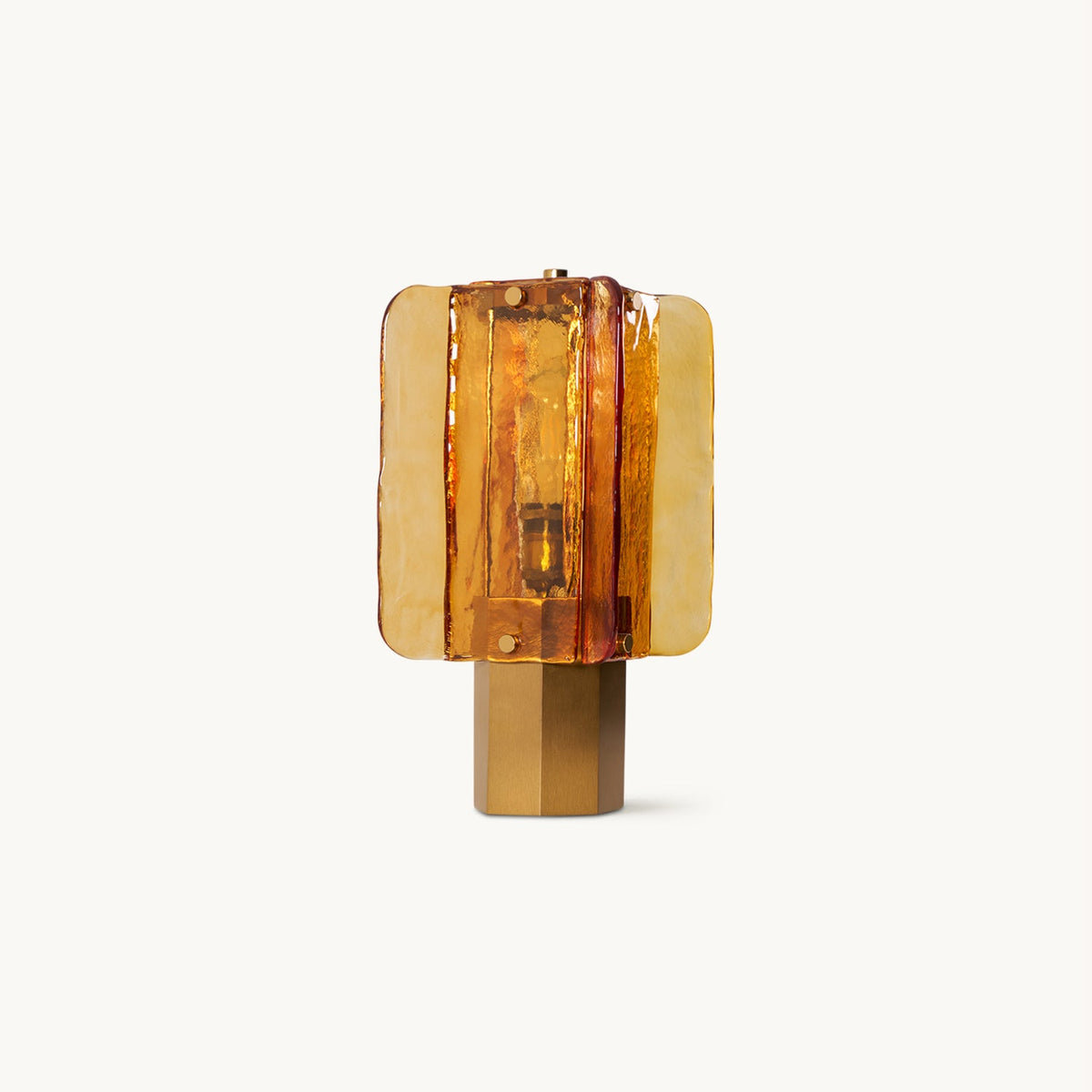 A Clérachic table lamp on a plain white backdrop, with amber glass panels fanned around a lit bulb on a six-sided metal base.