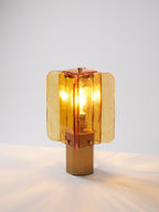 This Clérachic table lamp lit on a white surface, its glow reflecting in soft streaks across the table around the hexagonal base.