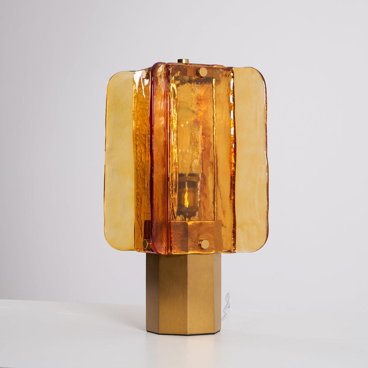 Unlit Clérachic table lamp on a white surface, showing the rippled amber glass panels and the bulb holder behind them.