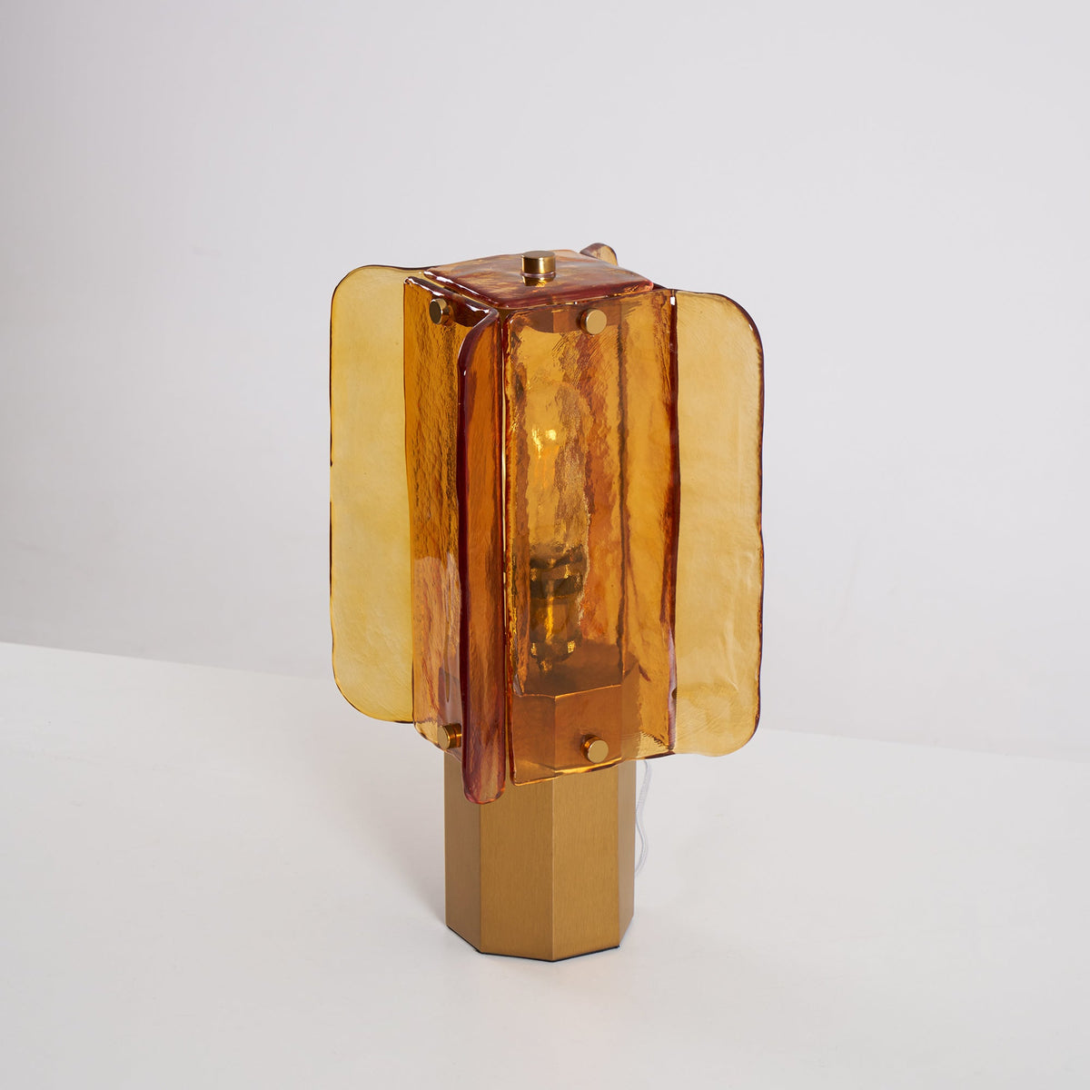 Unlit Clérachic table lamp turned slightly to one side, so the layered amber glass panels and the six-sided base show clearly.