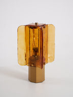 Clérachic table lamp unlit against a grey backdrop, the amber glass panels in front of a bulb above a plain metal base.