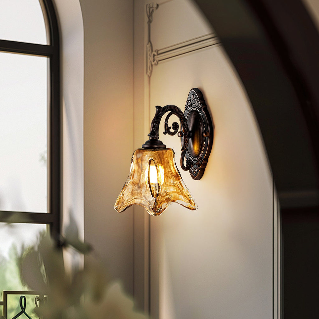 Beside an arched window, a lit Clérachic wall lamp glows warm on a pale wall, its amber glass shade flaring at the rim.