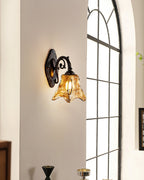 Further back, a Clérachic wall lamp glows on a pale wall beside an arched window with fine black glazing bars.