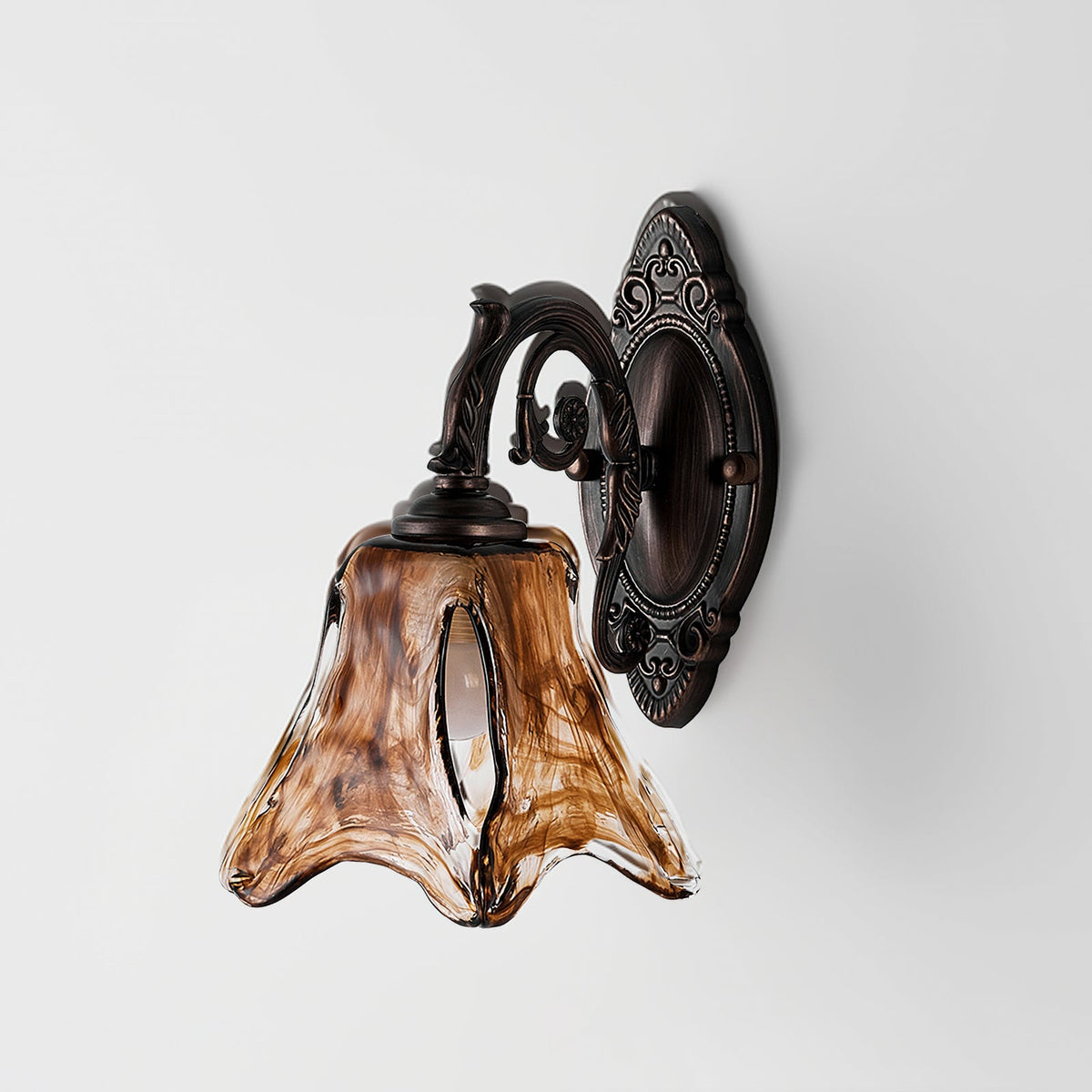 Side view of an unlit Clérachic wall lamp, its streaked amber glass shade hanging from a scrolled red bronze arm.