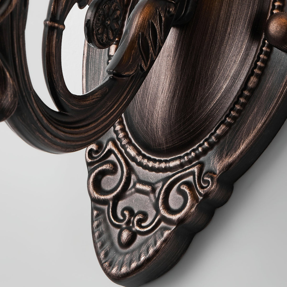 Close view of the oval backplate of this Clérachic wall lamp, with beaded edging and scrolled red bronze detail.