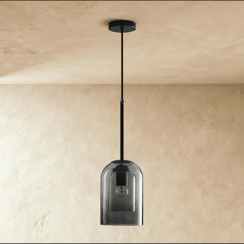 Clérachic's smoky gray glass pendant hangs unlit from a black cord against a plain plaster wall.