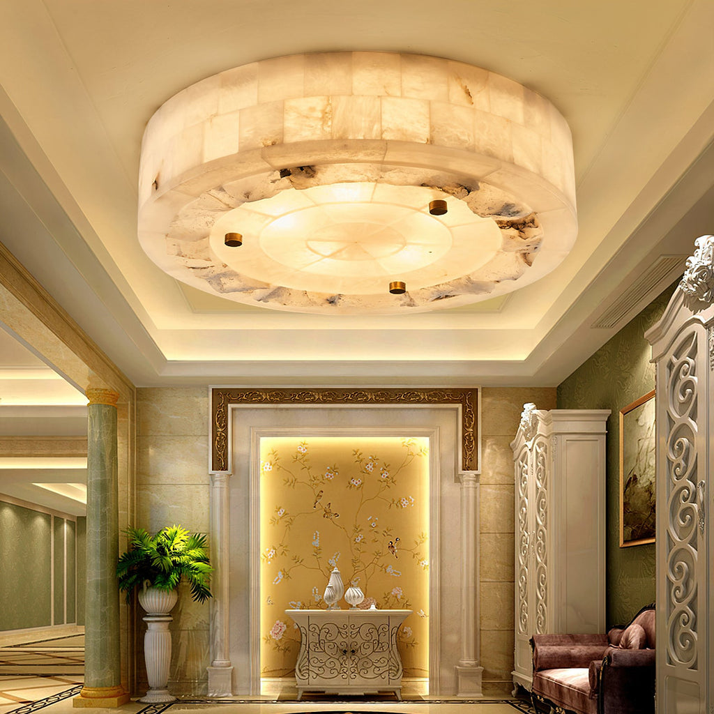 Round Clérachic alabaster ceiling light glowing in a recessed cove ceiling, above a hallway with columns and a gold wall panel.