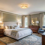 Round Clérachic alabaster ceiling light on a pale ceiling above a bedroom with sage walls, a white bed and a blue rug.