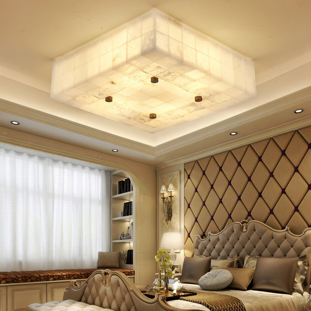 Large square Clérachic alabaster ceiling light in a recessed ceiling above a bed with a diamond-quilted headboard.