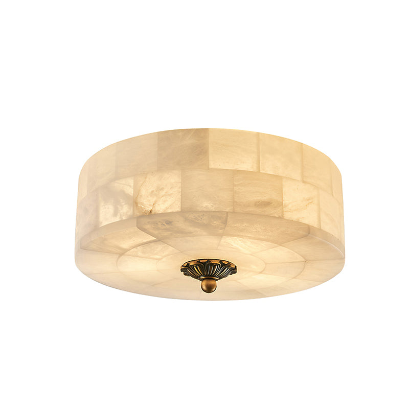 Larger round alabaster ceiling light from Clérachic, its tiled stone side lit warm and a brass centre cap beneath, on white.
