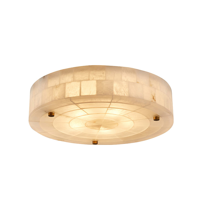 Wide round Clérachic alabaster ceiling light with a smooth glowing underside, three brass studs and a tiled stone rim.