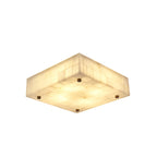 Shallow square Clérachic alabaster ceiling light, lit, with a tiled stone side and a brass stud set at each corner, on white.