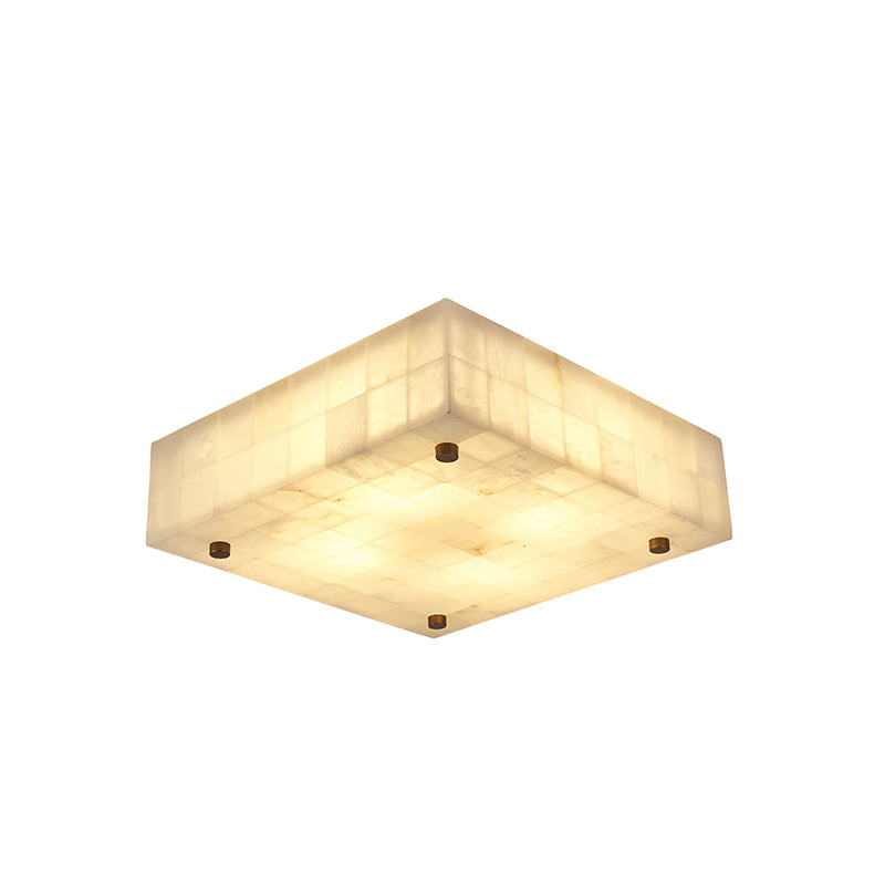 Shallow square Clérachic alabaster ceiling light, lit, with a tiled stone side and a brass stud set at each corner, on white.