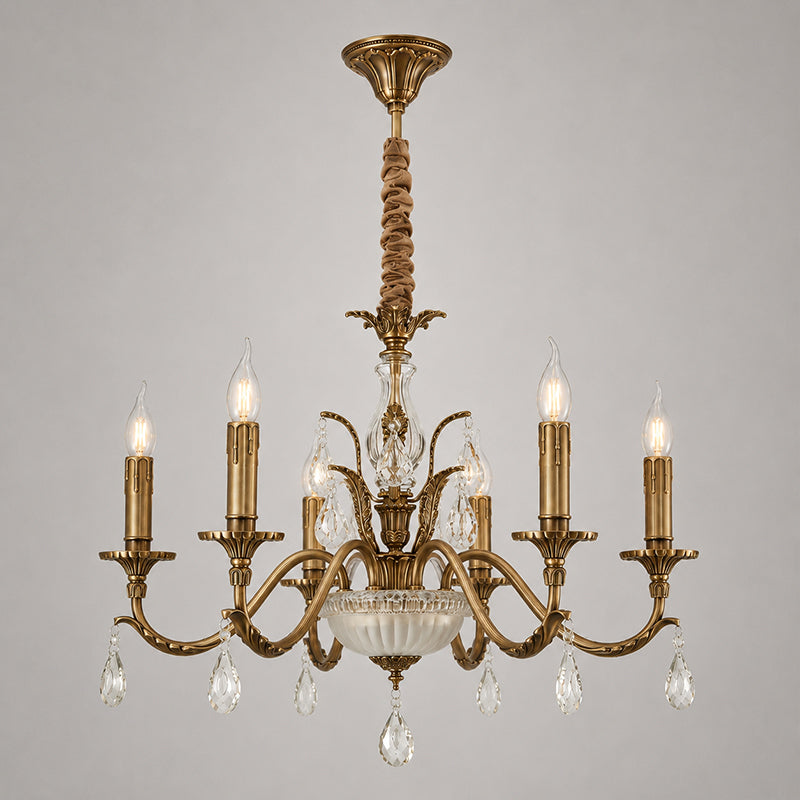 This Clérachic antique brass chandelier on a grey backdrop shows its curved arms, candle lights, glass bowl and crystal drops.