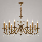 A larger Clérachic antique brass chandelier on grey, with ten candle-style lights and two tiers of crystal drops beneath its arms.