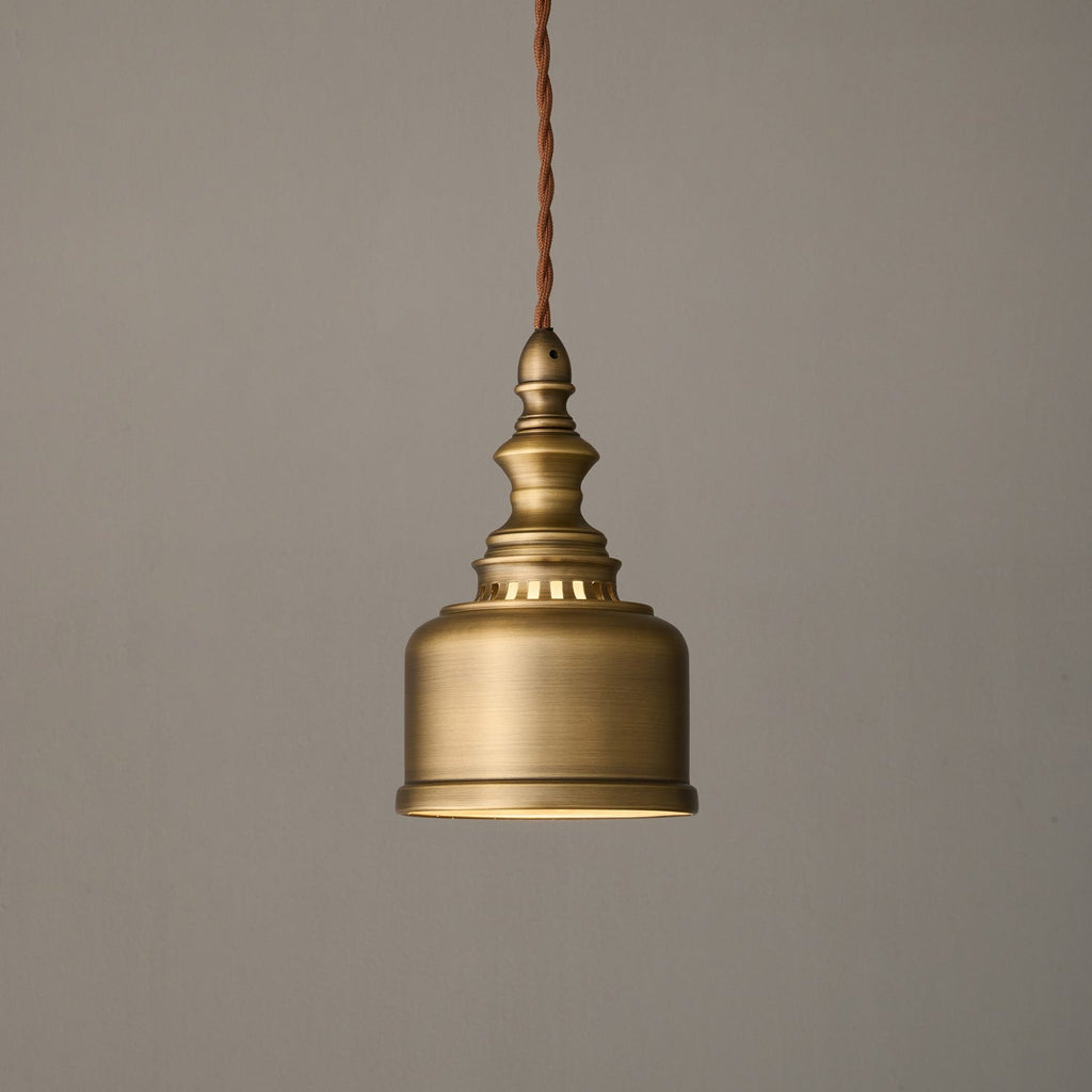 Side view of the brushed brass bell shade and slotted collar of this Clérachic pendant, hanging unlit on its cord.