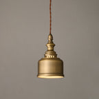 Smaller in the frame, this Clérachic brass dome pendant glows softly from within, its twisted cord running up out of view.