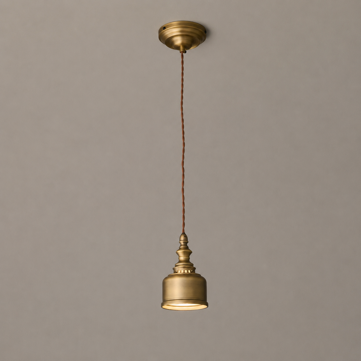 The same long drop with the Clérachic brass dome lit, a small canopy at the ceiling and a thin twisted cord between.