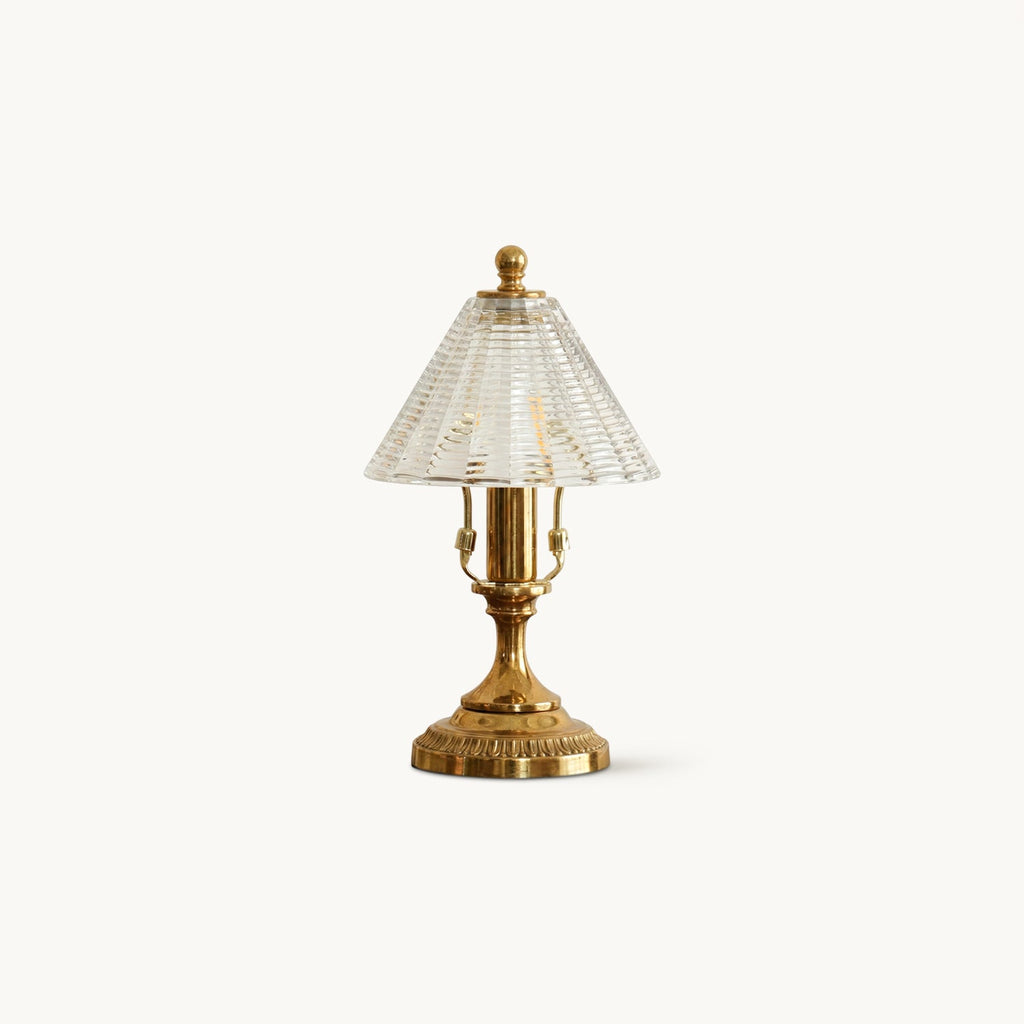 A Clérachic table lamp on a plain off-white backdrop, with an antique brass base and a clear ribbed glass cone shade.
