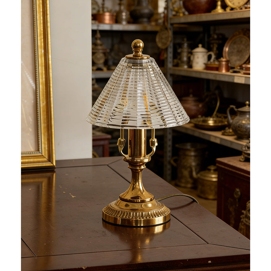 Unlit Clérachic table lamp showing the clear ribbed glass cone shade and brass candle-style stem on a dark wood surface.