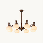 A Clérachic chandelier in antique bronze with cream glass shades on curved arms, shown on a plain white backdrop.