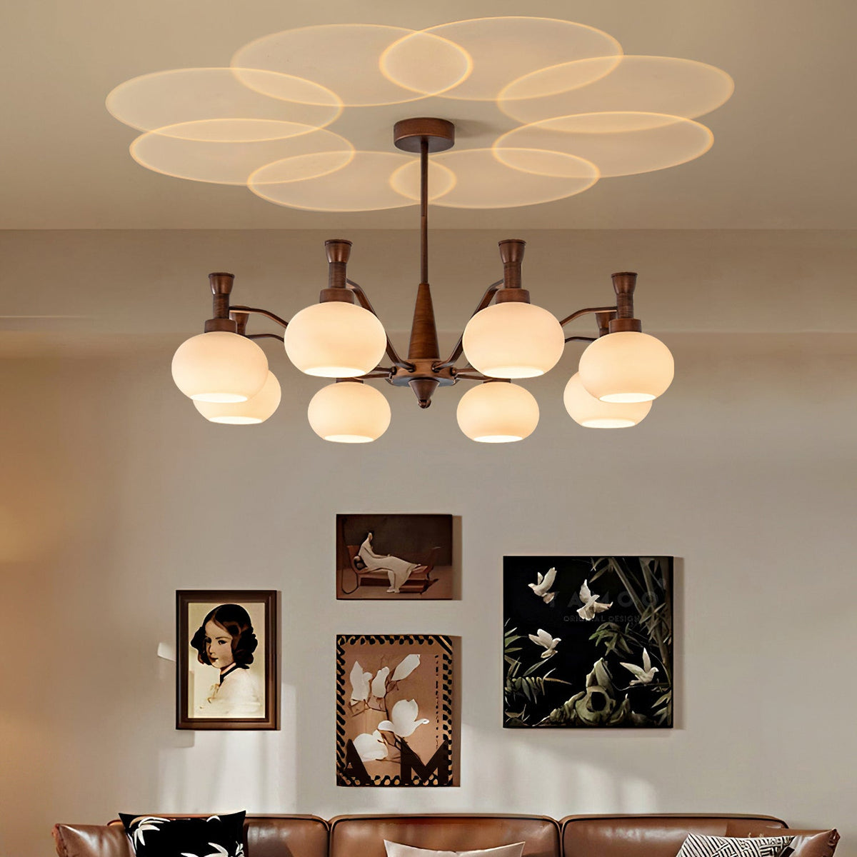 Overlapping circles of light spread across the ceiling from this Clérachic antique bronze chandelier, above framed prints and a leather sofa.