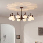 This Clérachic chandelier lit in a corner room with arched openings and slatted blinds, its glass shades casting a petal pattern on the ceiling.