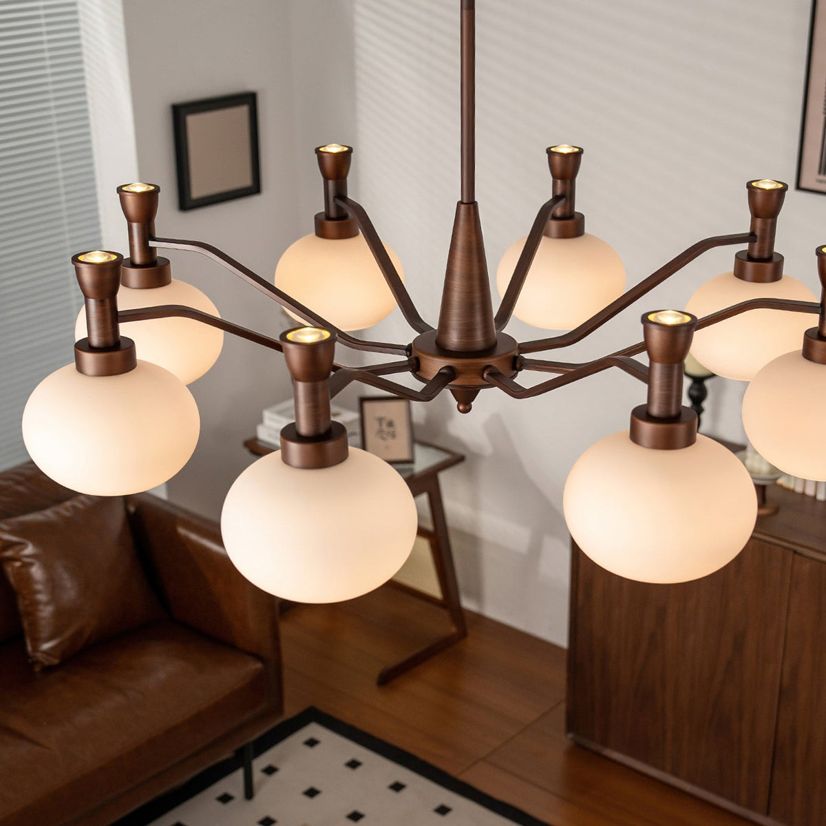 Looking down through the arms of this Clérachic chandelier at a leather sofa, a wooden cabinet and a black-and-white tiled floor.