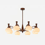 The trumpet-topped arm version of this Clérachic chandelier, unlit, with cream glass shades and a bronze stem on a white backdrop.