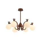 A Clérachic chandelier with a slimmer curved-arm frame in antique bronze and round cream glass globes, on a white backdrop.
