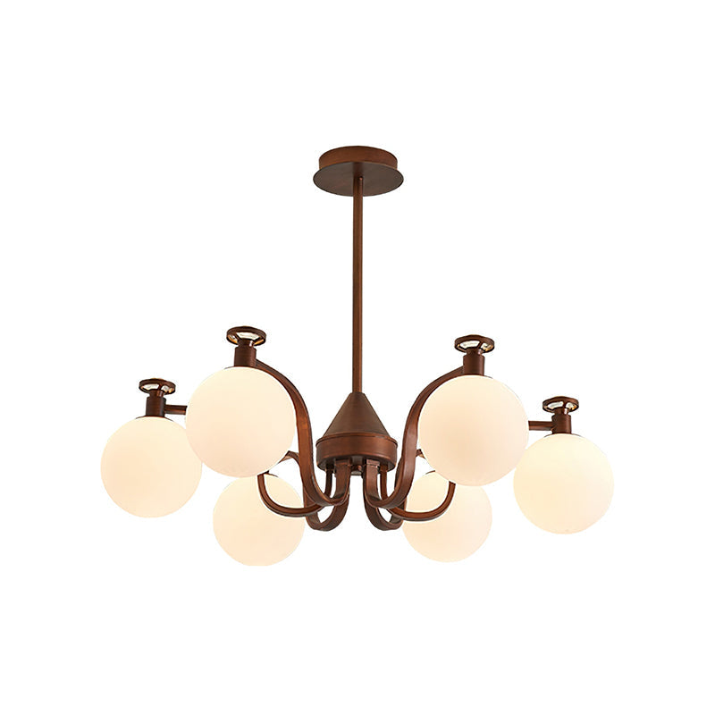 A Clérachic chandelier with a slimmer curved-arm frame in antique bronze and round cream glass globes, on a white backdrop.