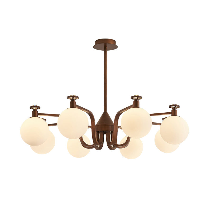 Round cream globes on a swept-arm antique bronze frame, this Clérachic chandelier hangs from a rod and flat ceiling plate on white.