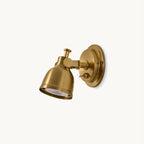 Antique gold Clérachic wall light with a domed shade, round backplate and small toggle switch, shown on a plain off-white backdrop.